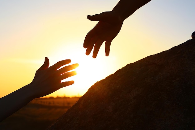 Hiker helping friend at sunset — halfway house admission process support concept
